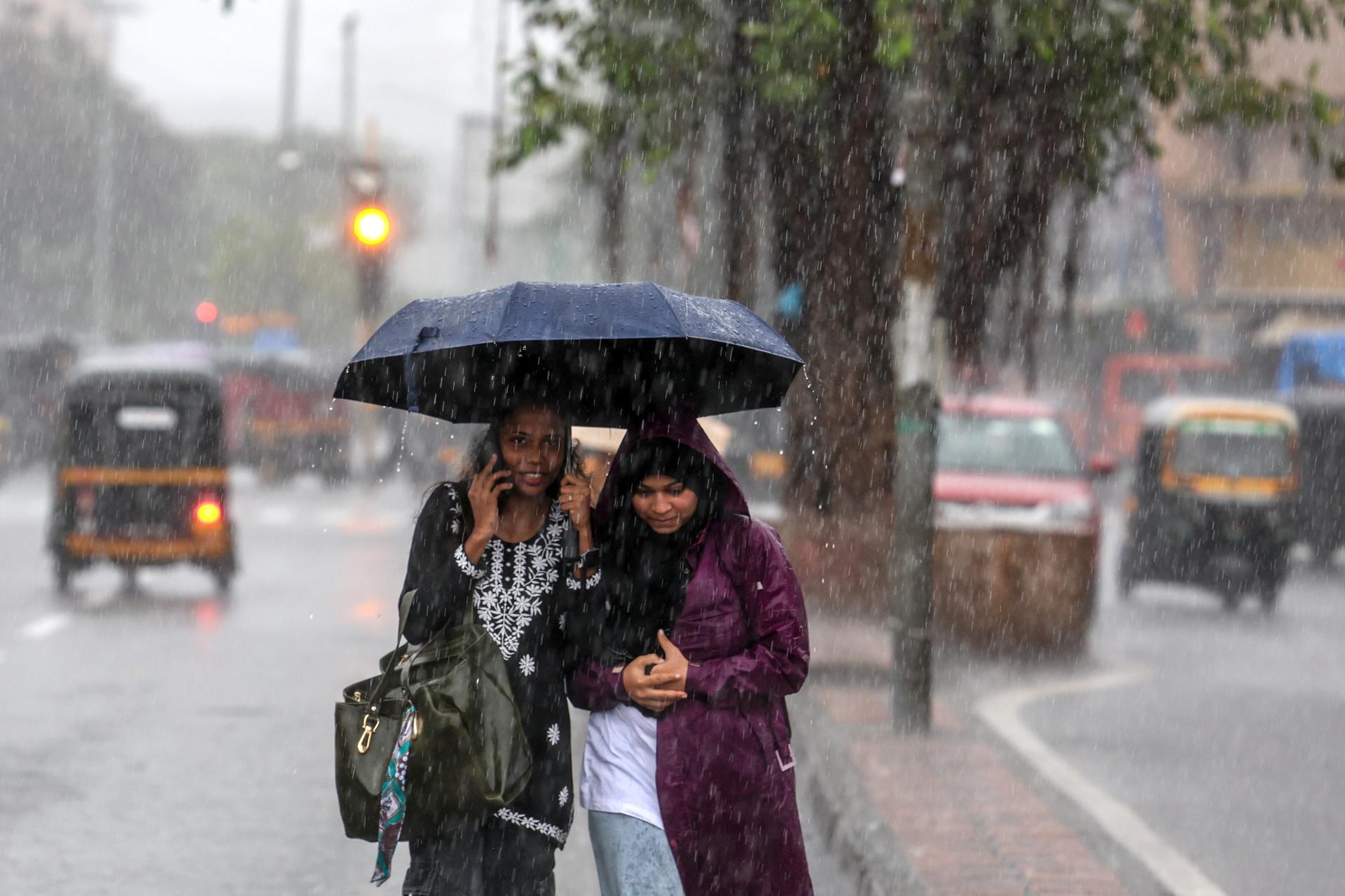 Varias personas se protegen de la lluvia en Bombay, la India. EFE/EPA/DIVYAKANT SOLANKI
