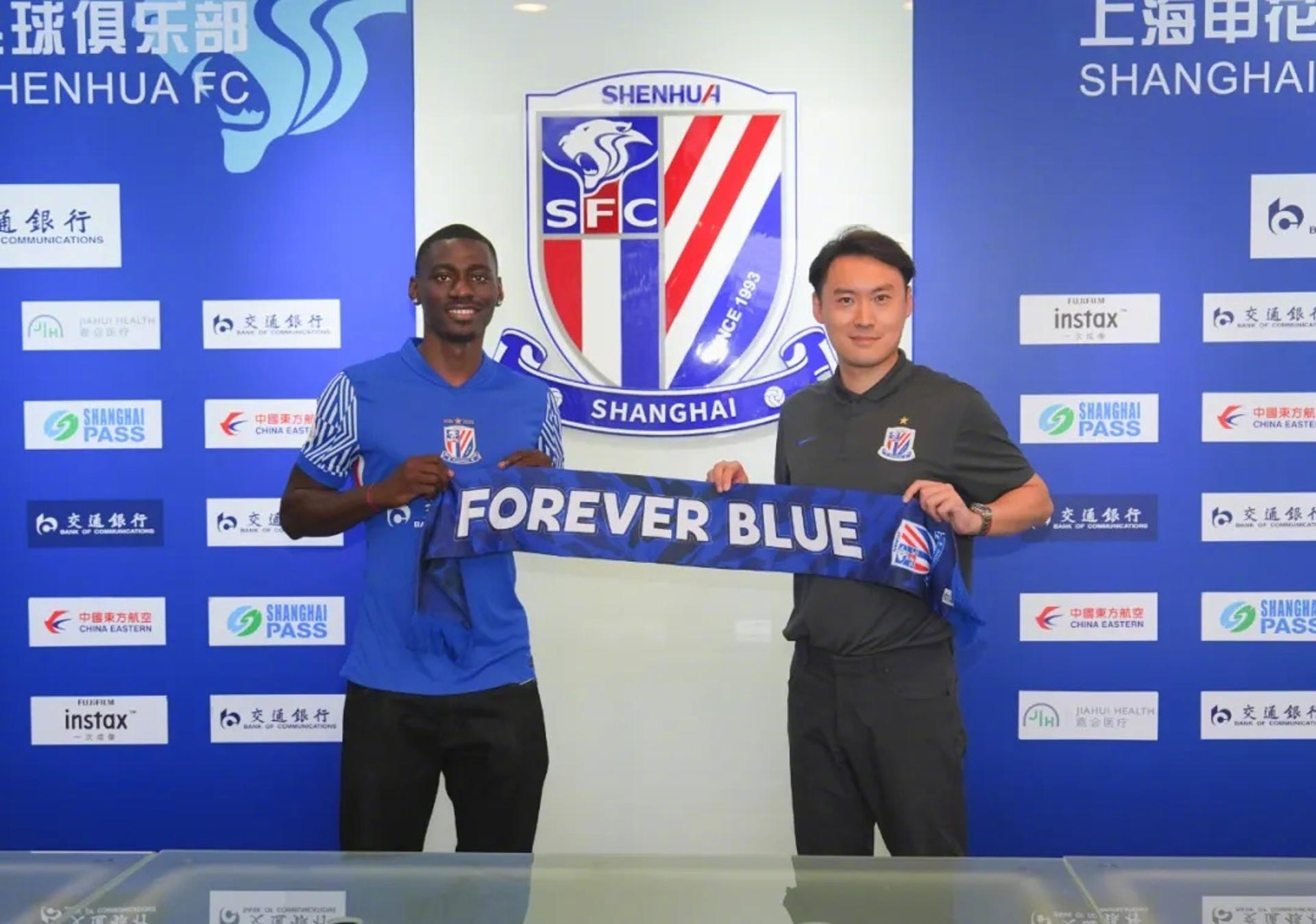 El delantero ecuatoguineano Luis Asué (i) posa con la camiseta de su nuevo equipo, el Shanghái Shenhua, durante su presentación oficial en Shanghái. Asué, de 23 años, se convierte en el primer futbolista de Guinea Ecuatorial en jugar en la Superliga china. EFE/Shanghái Shenhua *****SOLO USO EDITORIAL/SOLO DISPONIBLE PARA ILUSTRAR LA NOTICIA QUE ACOMPAÑA (CRÉDITO OBLIGATORIO) *****