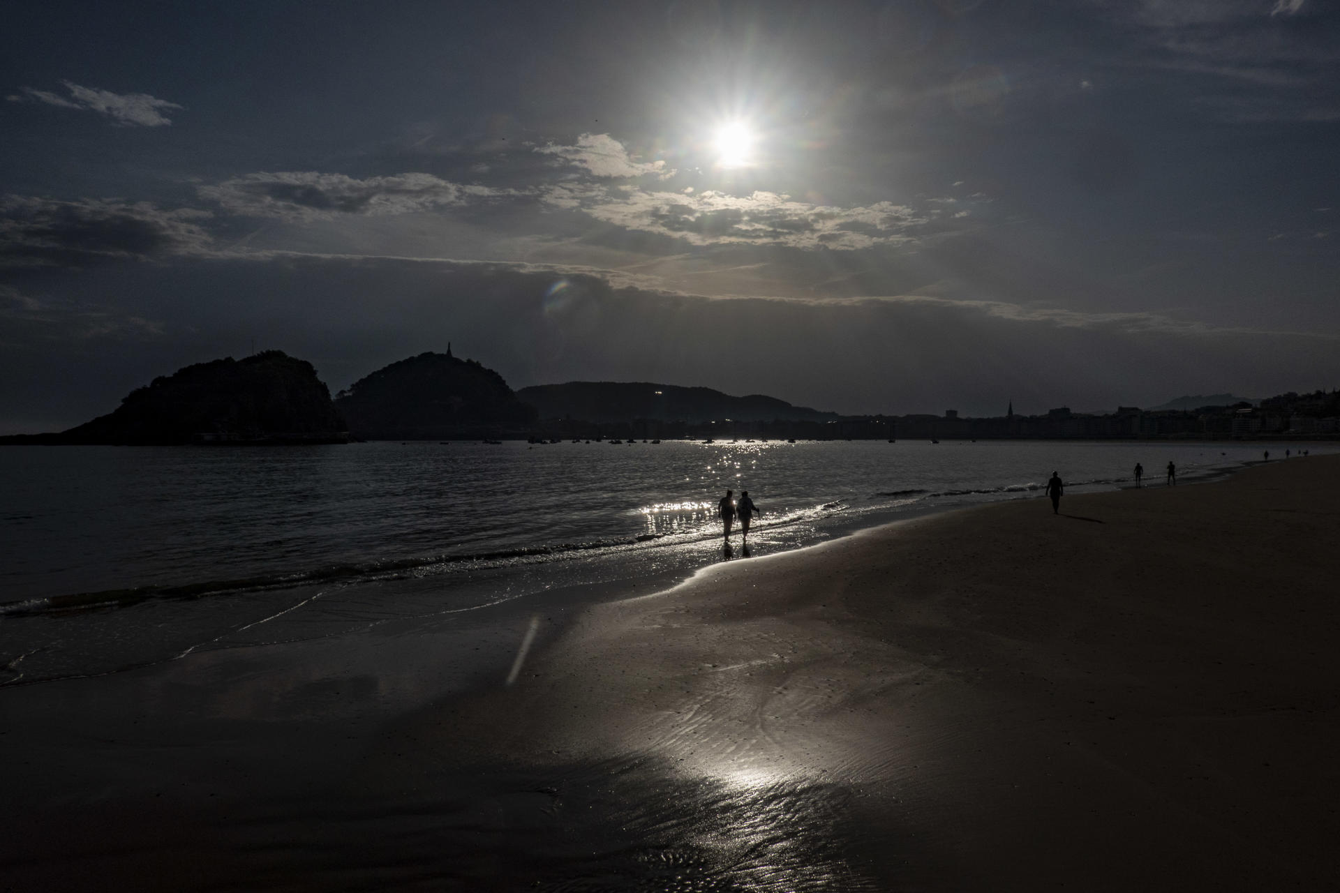 Varias personas pasean a primera hora de este miércoles por la orilla de la playa de Ondarreta. EFE/Javier Etxezarreta