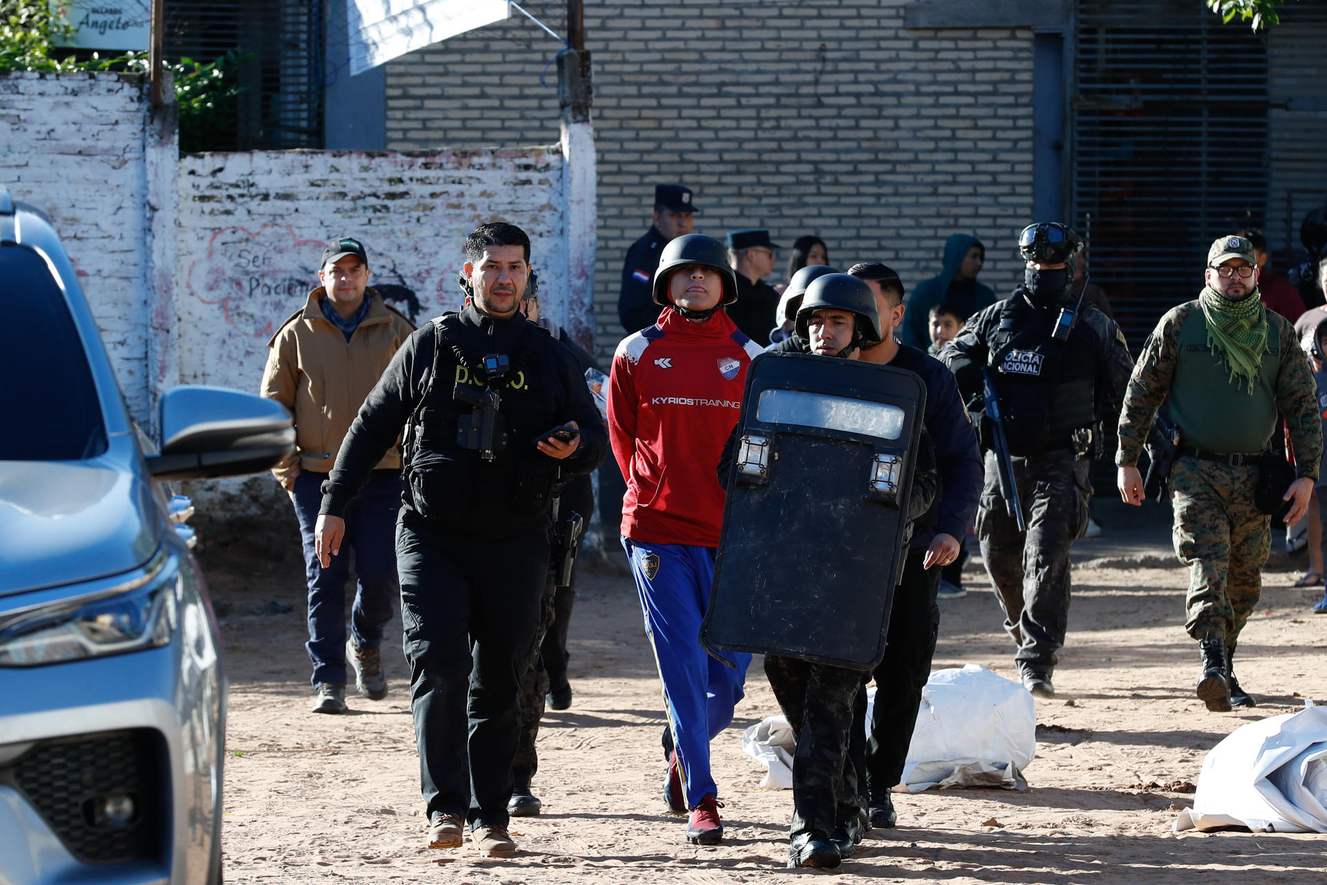 Integrantes de las Fuerzas de Operaciones Policiales Especiales (FOPE) trasladan a un detenido este miércoles durante el operativo policial 'Dominatus' en el barrio Ricardo Brugada, en Asunción (Paraguay). EFE/ Juan Pablo Pino