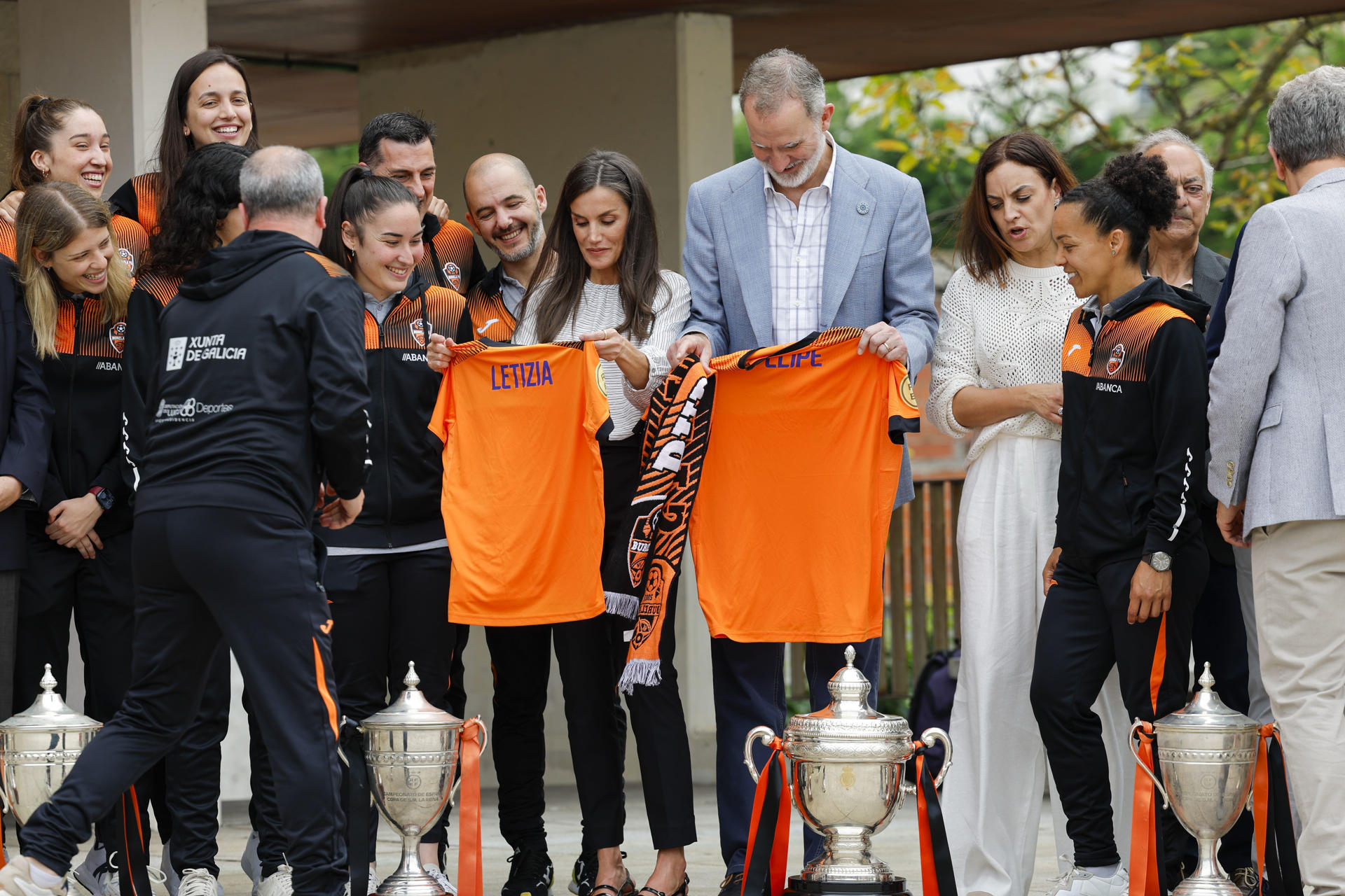 La reina Letizia (c-izda) y el rey Felipe VI (c-dcha), en presencia de la alcaldesa de Burela (Lugo), Carmela López (2d), reciben camisetas con sus nombres durante su encuentro con las jugadoras del Club Deportivo Burela Fútbol Sala durante su vista este martes a la localidad para interesarse de primera mano por la realidad del sector pesquero de A Mariña lucense. EFE/ Lavandeira Jr.