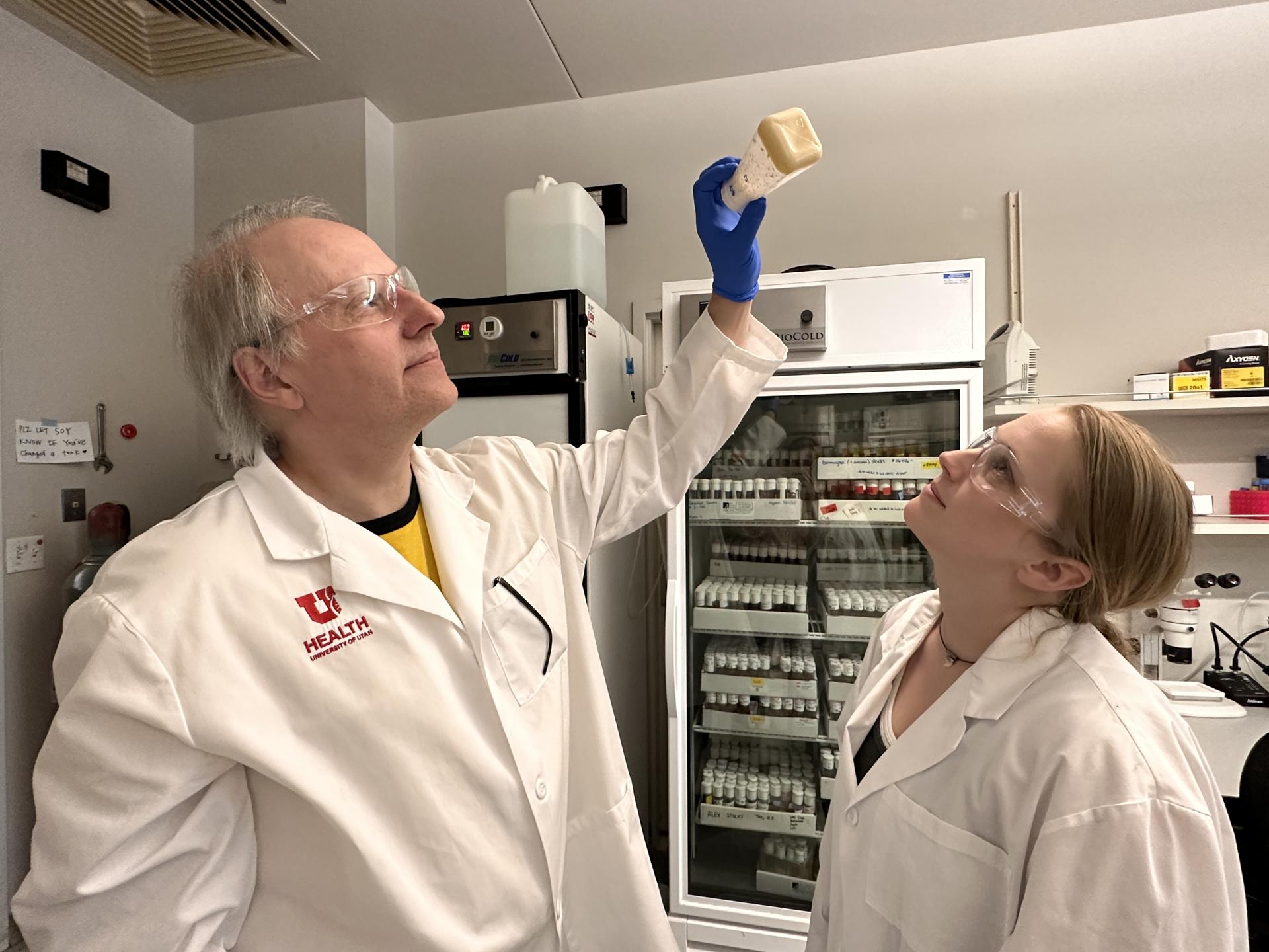 Los investigadores de Psiquiatría de la Universidad de Utah, en Estados Unidos, Adrian Rothenfluh (iizquierda) y Pearl Cummins-Beebee (derecha) inspeccionan un frasco de moscas de la fruta en el laboratorio. Este insecto, que comparte genes con los humanos, está desvelando la biología de la adicción a la cocaína, llave para acelerar el desarrollo de terapias. Fotografía facilitada por Caitlyn Harris / University of Utah Health. EFE