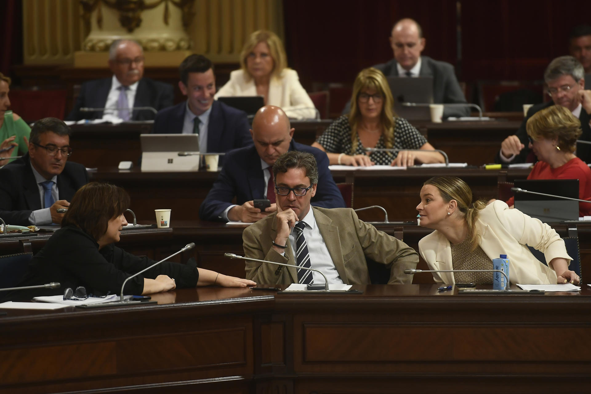 La presidenta del Govern balear, Marga Prohens (d), junto al vicepresidente, Antoni Costa (c), conversa con la consellera de Presidencia, Antònia María Estarellas (i), durante el Pleno del Parlament Balear, este martes en Palma. EFE/ Miquel A. Borràs