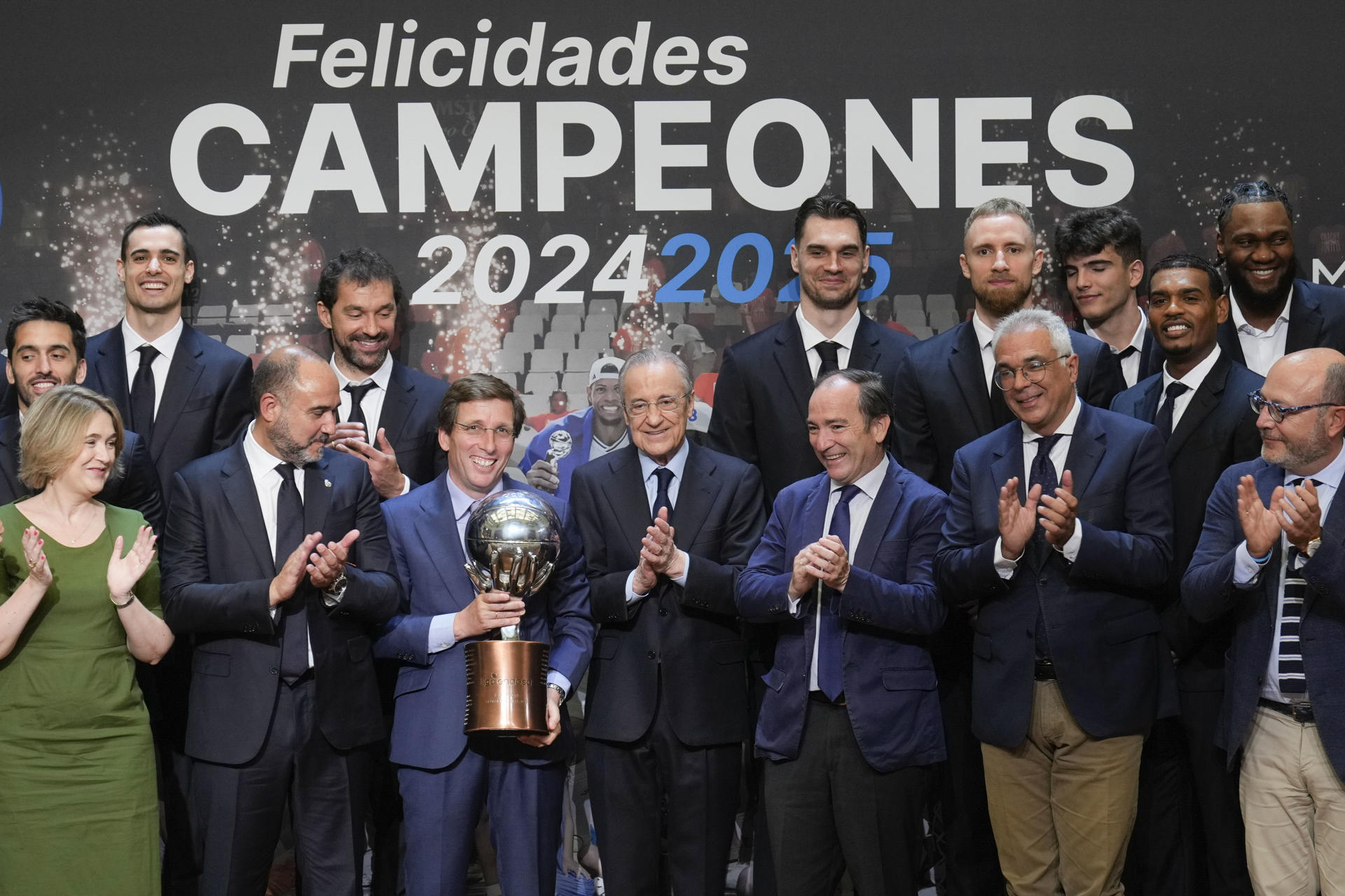 El alcalde de Madrid, José Luis Martínez-Almeida (3i, delante), el presidente del Real Madrid, Florentino Pérez (c, delante), y el capitán del Real Madrid de baloncesto, Sergio Llull (3i, detrás), durante la recepción a los jugadores, junta directiva y técnicos del Real Madrid de baloncesto, campeón de la Liga Endesa 2024-25, este viernes en el ayuntamiento de Madrid. EFE/ Borja Sánchez-Trillo