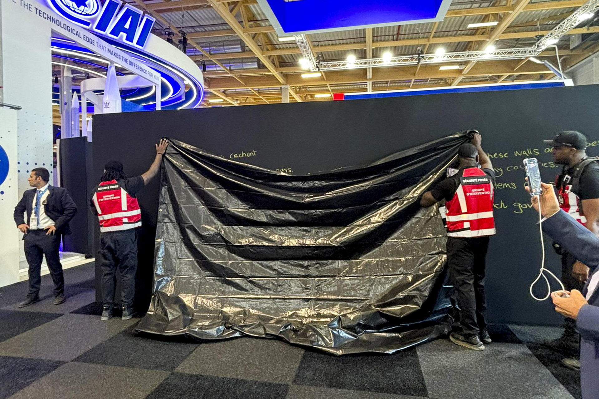Personal del Salón Internacional de Aeronáutica y del Espacio de Le Bourget, la mayor feria del sector, cubre con una lona un mensaje político a favor de Israel escrito por una trabajadora en el stand de la empresa israelí Rafael, especializada en tecnología de defensa. EFE/ Rafael SOLO USO EDITORIAL/SOLO DISPONIBLE PARA ILUSTRAR LA NOTICIA QUE ACOMPAÑA (CRÉDITO OBLIGATORIO)