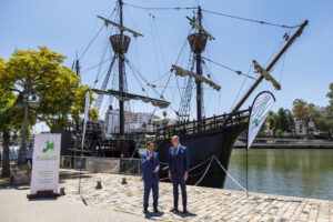 El presidente de la Junta de Andalucía, Juanma Moreno (i), junto al presidente de la CRPM (Conferencia de Regiones Periféricas Marítimas) y Consejero de la Región de Gotland (Suecia), Filip Reinhag, posan ante la reproducción de la Nao Victoria tras el acto de clausura de la I Jornada de la Asamblea General de la Comisión Arco Atlántico, que se desarrolla este jueves en el Centro Nao Victoria de Sevilla. EFE/ Julio Muñoz