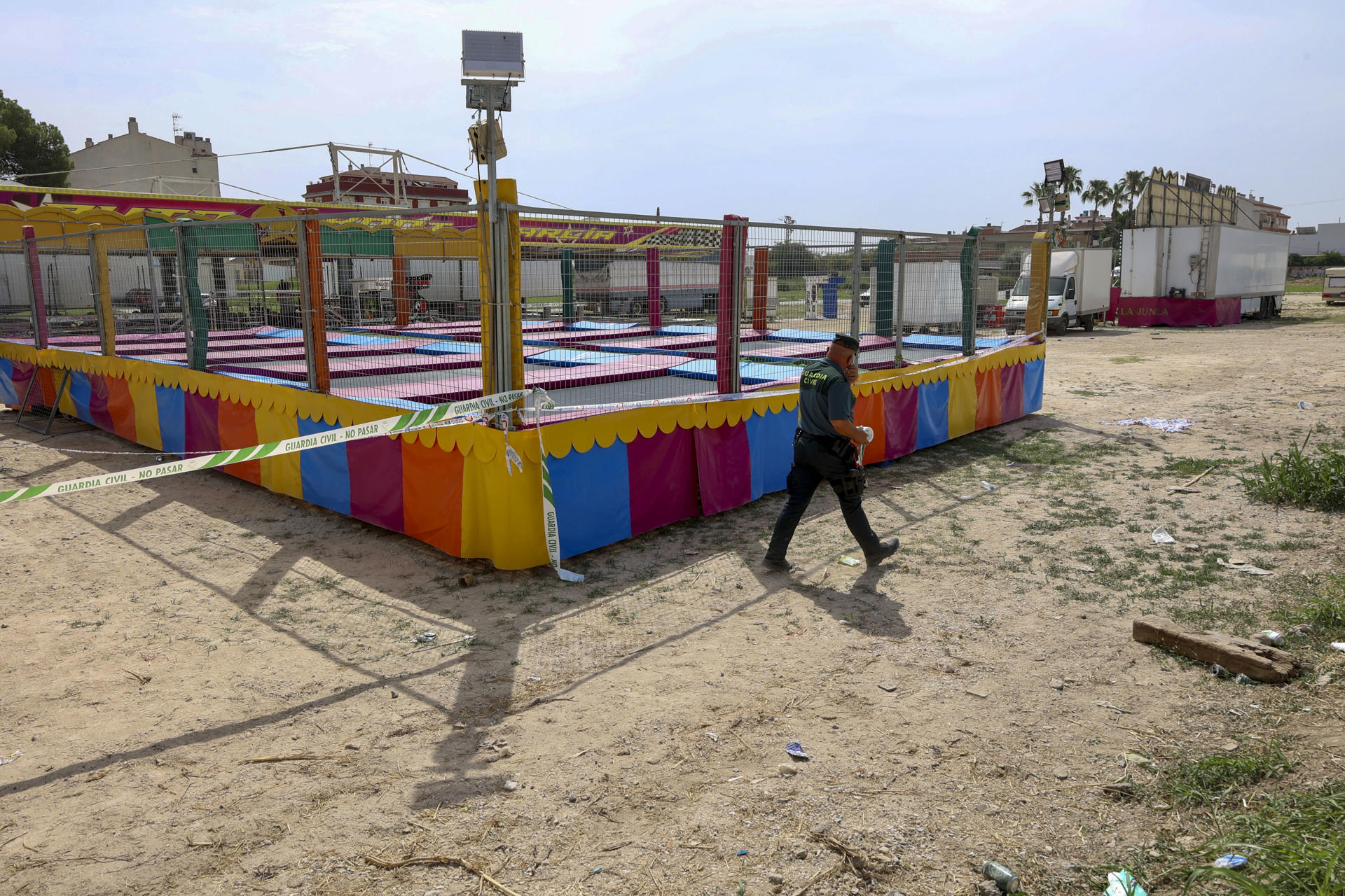 Un agente de la Guardia Civil precinta este domingo las camas elásticas del recinto ferial de la pedanía murciana de Alquerías después de que una niña de dos años falleciera esta madrugada al recibir una descarga eléctrica. EFE/ Juan Carlos Caval