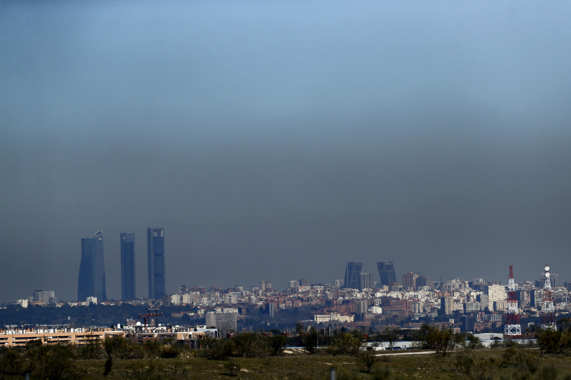 Vista de archivo de Madrid con el parque empresarial de las Cuatro Torres (i), en el Paseo de la Castellana de Madrid, y las Torres Kio (d), cubiertas por una 'boina' de contaminación. EFE/Juan Carlos Hidalgo