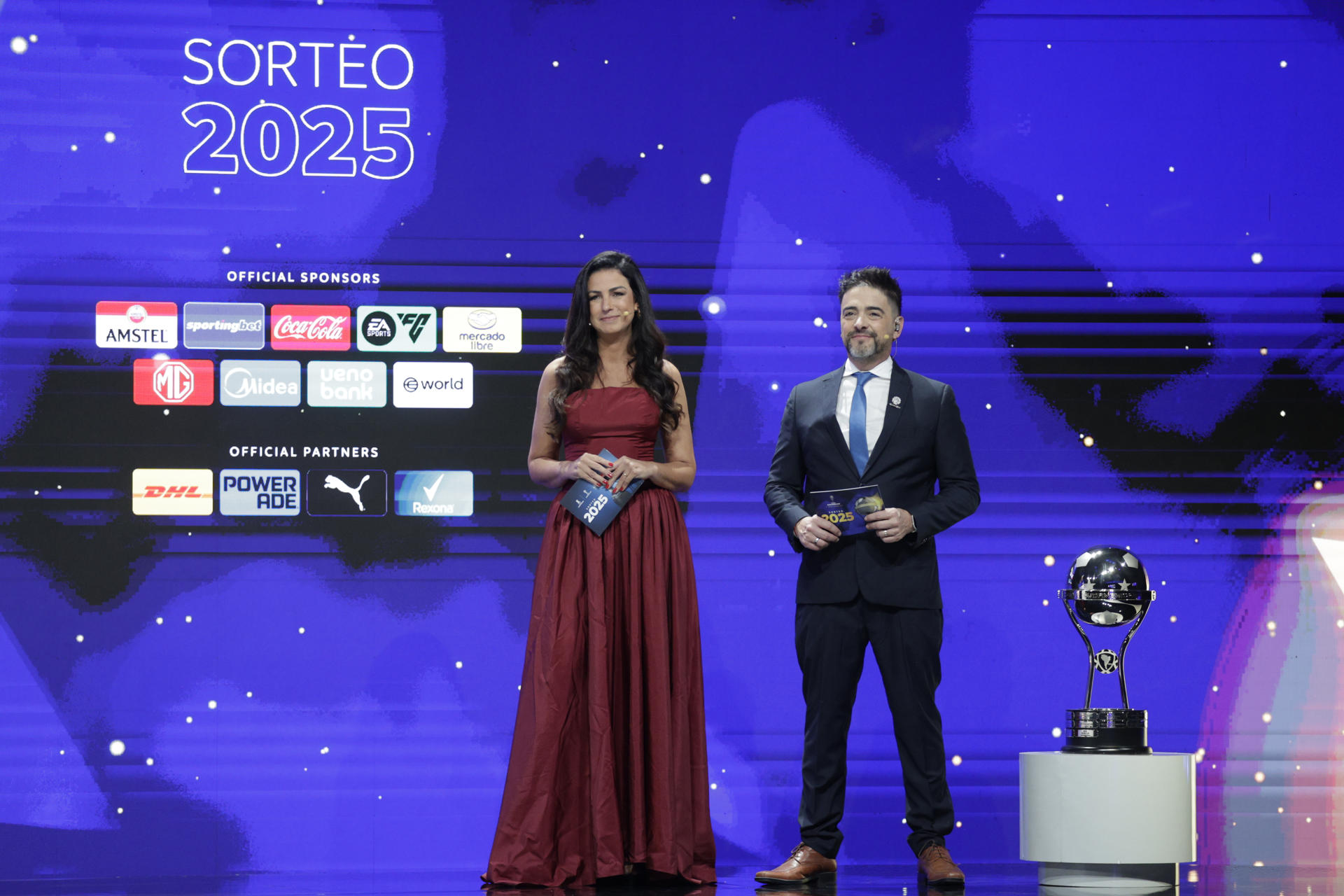 Los presentadores Helena Calil (i) y Juan José Buscalia hablan durante el sorteo de los octavos de final de la Copa Sudamericana 2025. EFE/Juan Pablo Pino
