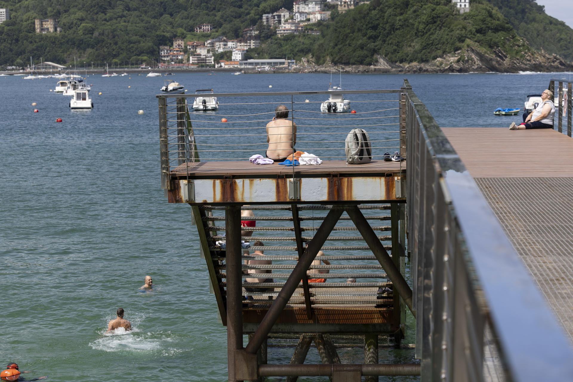 Varias personas disfrutan del buen tiempo este jueves en el Náutico de San Sebastián. EFE/Javier Etxezarreta