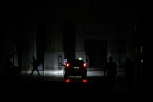 Personas caminan a oscuras por una calle andaluza, iluminada solo por los faros de un coche, durante el apagón del 28 de abril de 2025. EFE/ Jorge Zapata