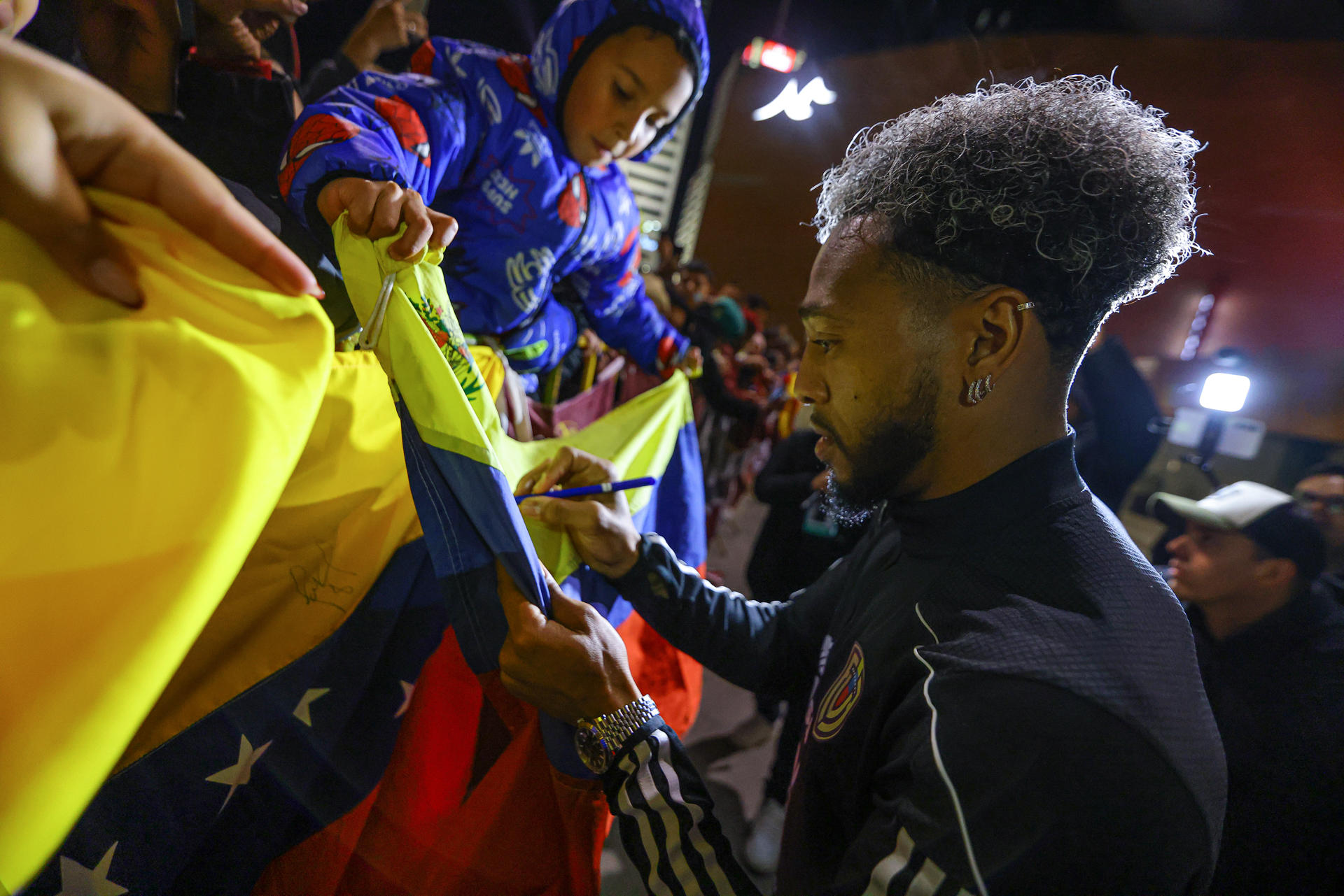 El jugador José Martínez firma una bandera durante el recibimiento a la selección de Venezuela frente al Hotel Hilton Garden en Montevideo. EFE/ Gastón Britos