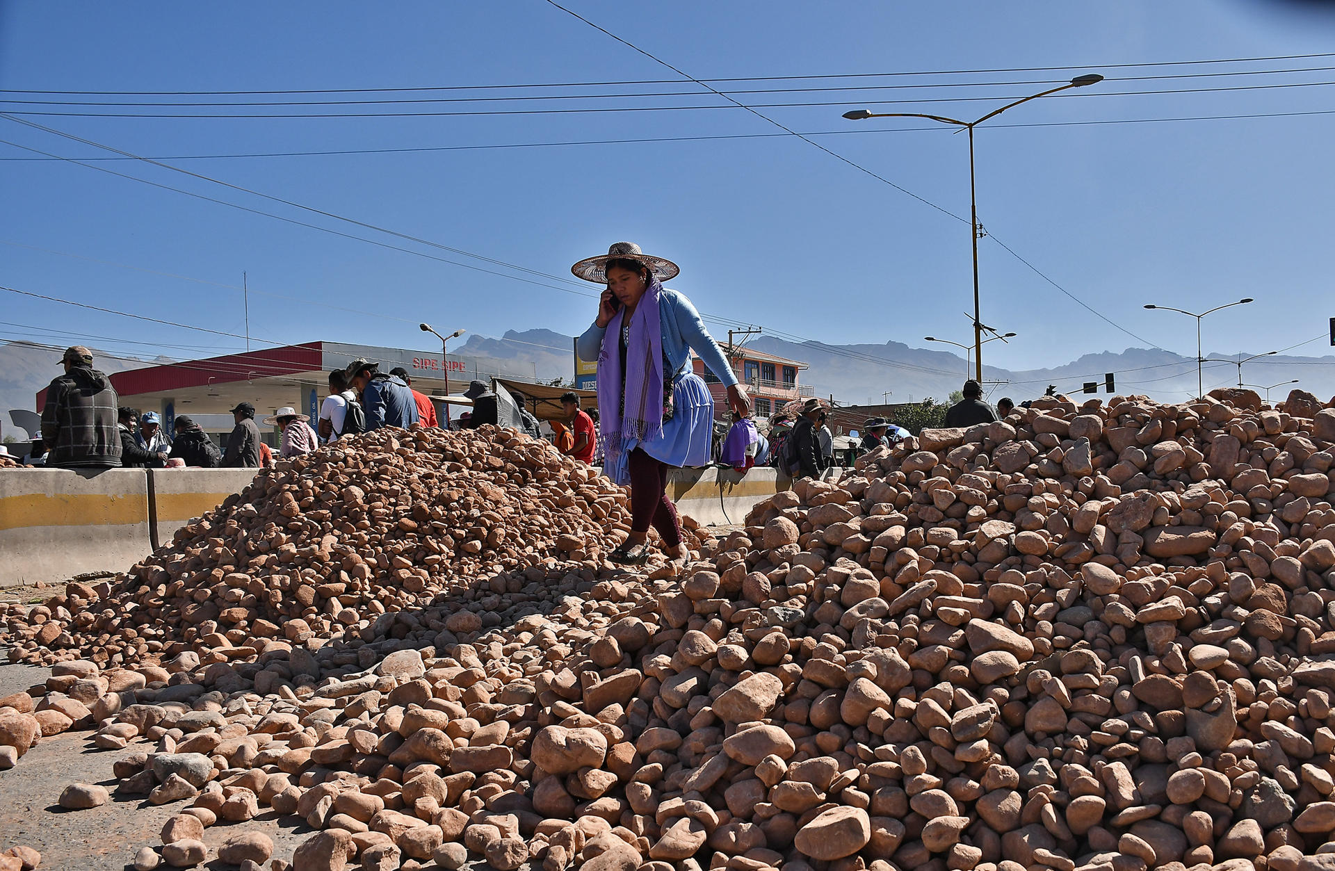 Una mujer fue captada este 2 de junio al pasar sobre un montículo de piedras, puestas por seguidores del exmandatario Evo Morales, que bloquean una carretera a la altura de la localidad de Sipe Sipe, en la región de Cochabamba (Bolivia). EFE/Jorge Ábrego