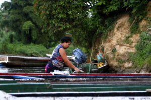 Una indígena limpia pescado en la orilla del río Tuquesa el 18 de junio de 2025, en el poblado de Bajo Chiquito, cerca de la selva del Darién (Panamá). EFE/Moncho Torres