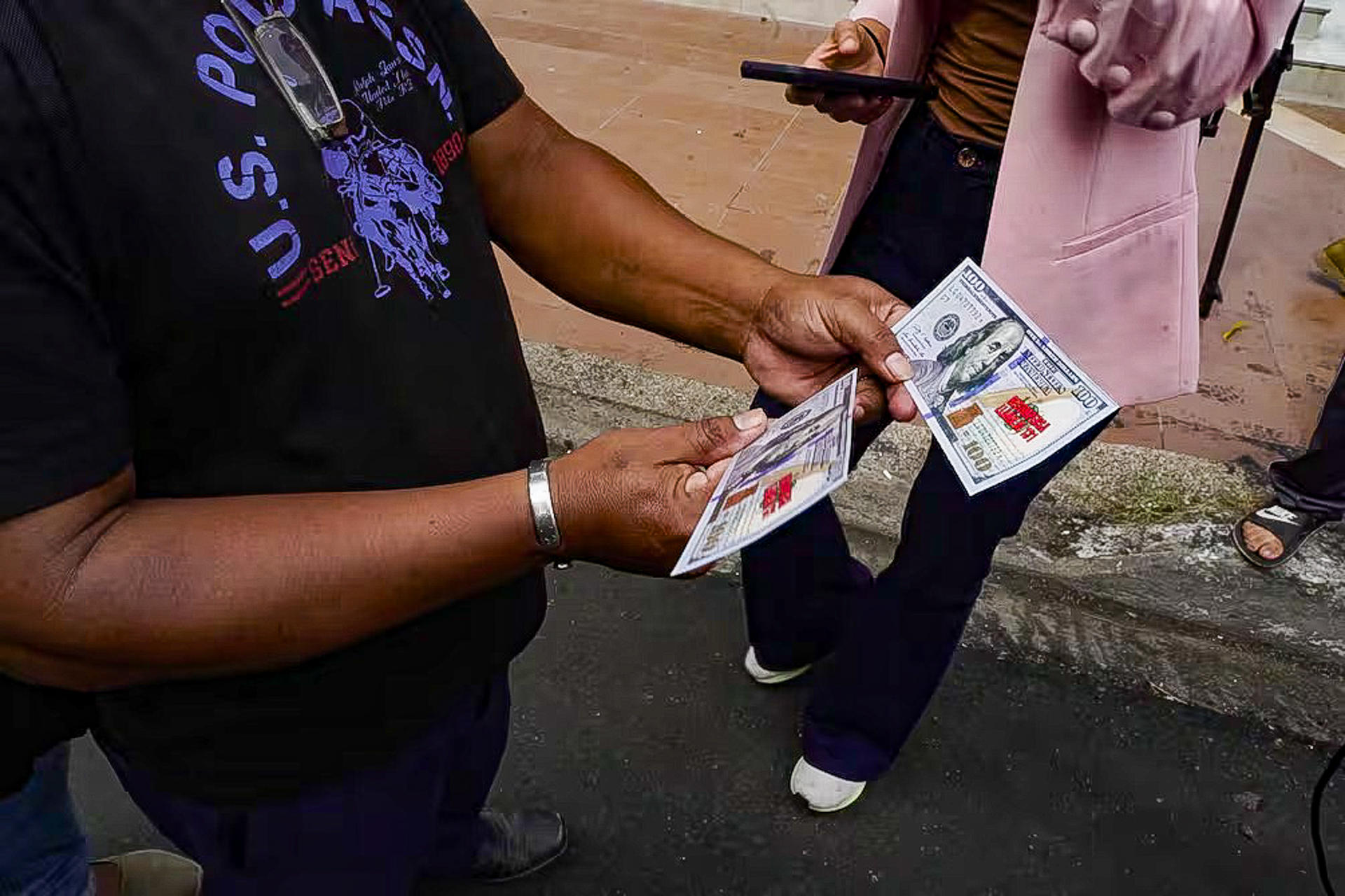 Fotografía cedida por las Fuerzas Armadas de Ecuador de una persona sosteniendo billetes falsos de 100 dólares que fueron lanzados desde un helicóptero con información sobre el plan de recompensas que se implementa a nivel nacional para incentivar las denuncias contra miembros de redes criminales o escondites de armas y drogas este viernes, en Guayaquil (Ecuador). EFE/ EFE/ Fuerzas Armadas De Ecuador
