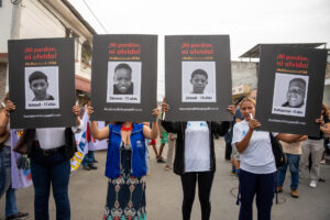 Fotografía de archivo de un grupo de personas al sostener carteles con las imágenes de los cuatro niños desaparecidos y hallados calcinados con signos de maltrato por parte de un grupo de militares, durante una marcha en el barrio Las Malvinas, en el sur de la ciudad de Guayaquil (Ecuador). EFE/Mauricio Torres