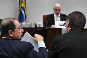 El abogado Celso Vilardi (i) sostiene un documento junto del expresidente de Brasil Jair Bolsonaro (d) en la segunda sesión de interrogatorio ante el Tribunal Supremo este martes, en Brasilia (Brasil). EFE/ Andre Borges