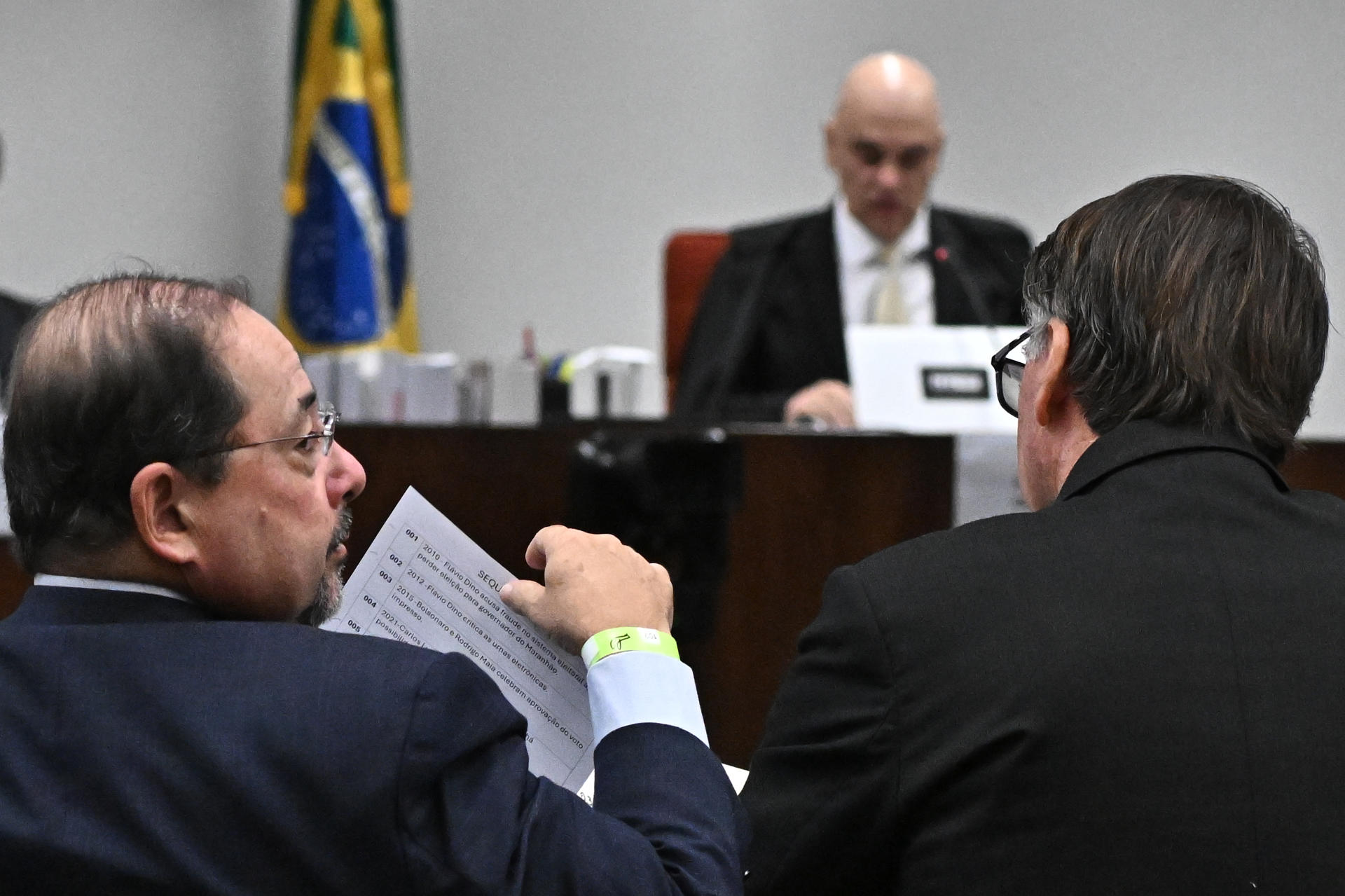 El abogado Celso Vilardi (i) sostiene un documento junto del expresidente de Brasil Jair Bolsonaro (d) en la segunda sesión de interrogatorio ante el Tribunal Supremo este martes, en Brasilia (Brasil). EFE/ Andre Borges