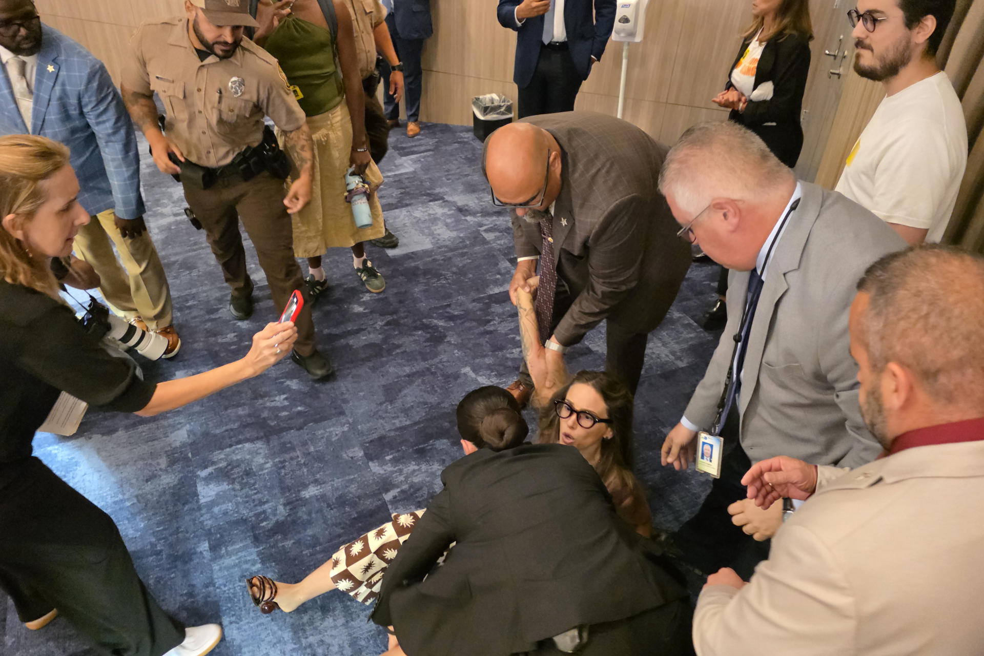 Un grupo de agentes forcejean con una activista para expulsarla del recinto donde se lleva a cabo la reunión de los comisionados de Miami-Dade este jueves, en la sede del gobierno local en Miami (EE.UU.). EFE/Alberto Boal