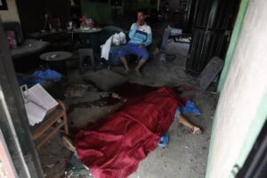 Un hombre espera al lado del cuerpo sin vida de una persona después de una explosión este martes en Guachinte, Jamundí (Colombia). EFE/Ernesto Guzmán