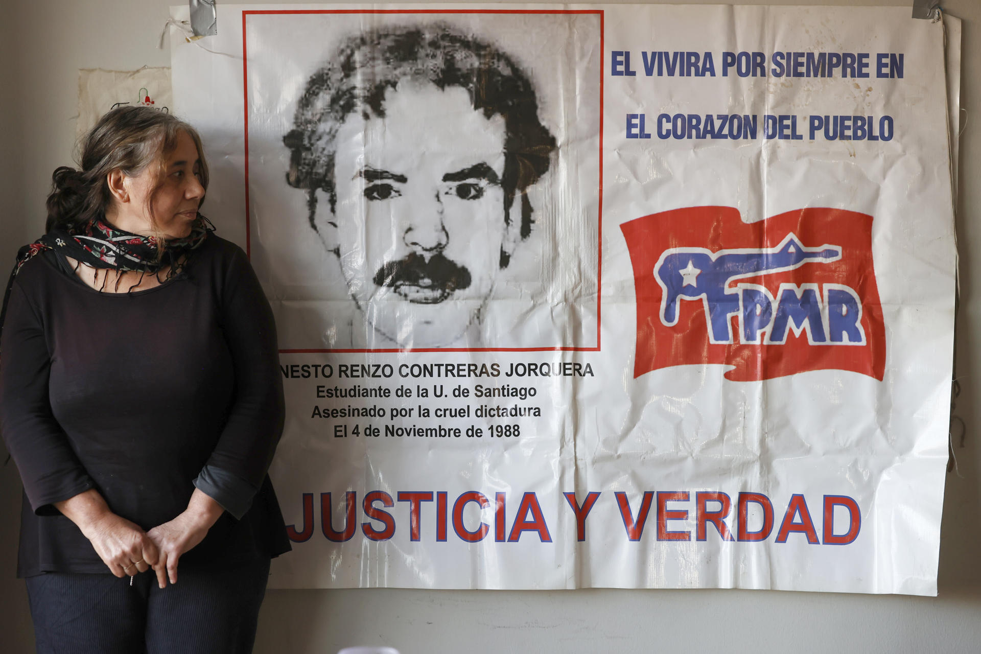 Fotografía del 27 de mayo de 2025 de Claudia, colaboradora anónima con la resistencia contra la dictadura de Pinochet, posando junto a un cartel homenaje a su expareja, el exguerrillero del Frente Patriótico Manuel Rodríguez (FPMR), Renzo Conteras, en Santiago (Chile). EFE/ Elvis González