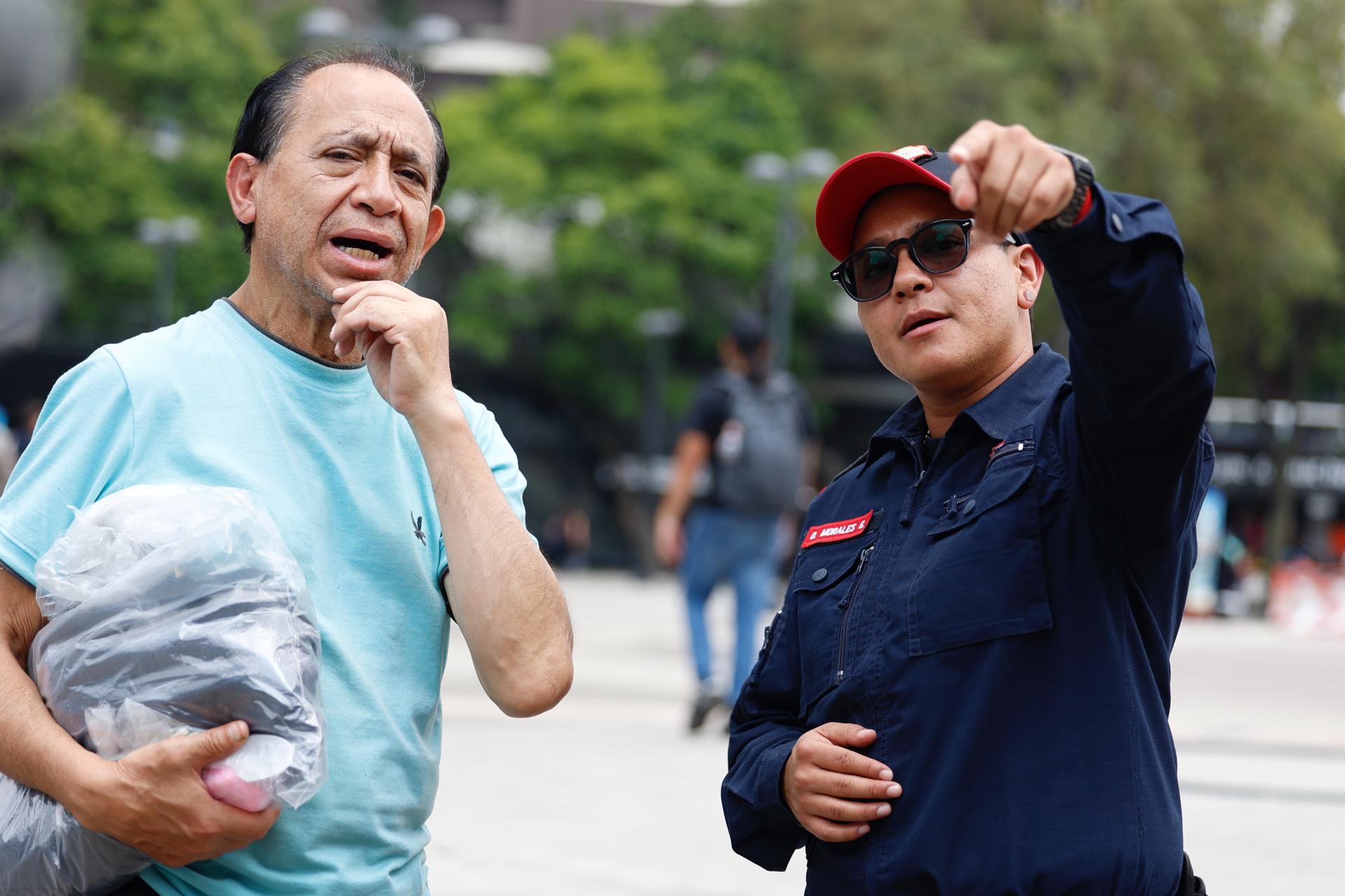 El oficial de la Policía Bancaria Industrial (PBI), Orel Morales (d), da indicaciones a una persona este jueves en Ciudad México (México). EFE/ Sáshenka Gutiérrez