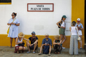 Unos turistas descansaban este sábado a la sombra en la entrada de la Plaza de Toros de la Maestranza de Sevilla. EFE/ Julio Muñoz