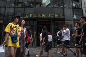 Fotografía de archivo que muestra a ciudadanos chinos que pasan frente a una sucursal de la cadena estadounidense de café Starbucks en Pekín, China. EFE/EPA/ROMAN PILIPEY