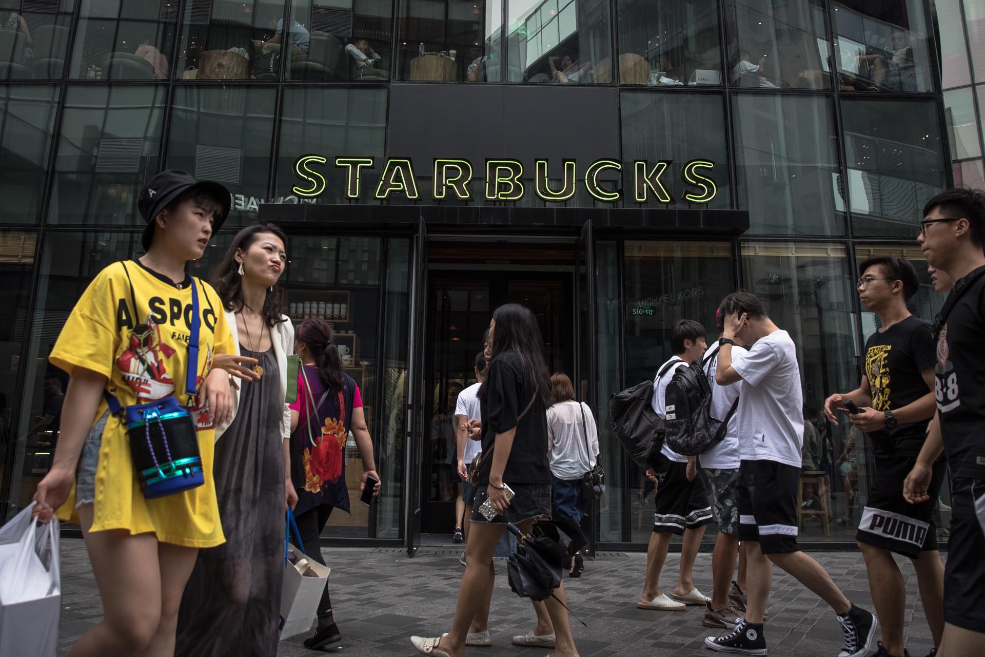 Fotografía de archivo que muestra a ciudadanos chinos que pasan frente a una sucursal de la cadena estadounidense de café Starbucks en Pekín, China. EFE/EPA/ROMAN PILIPEY