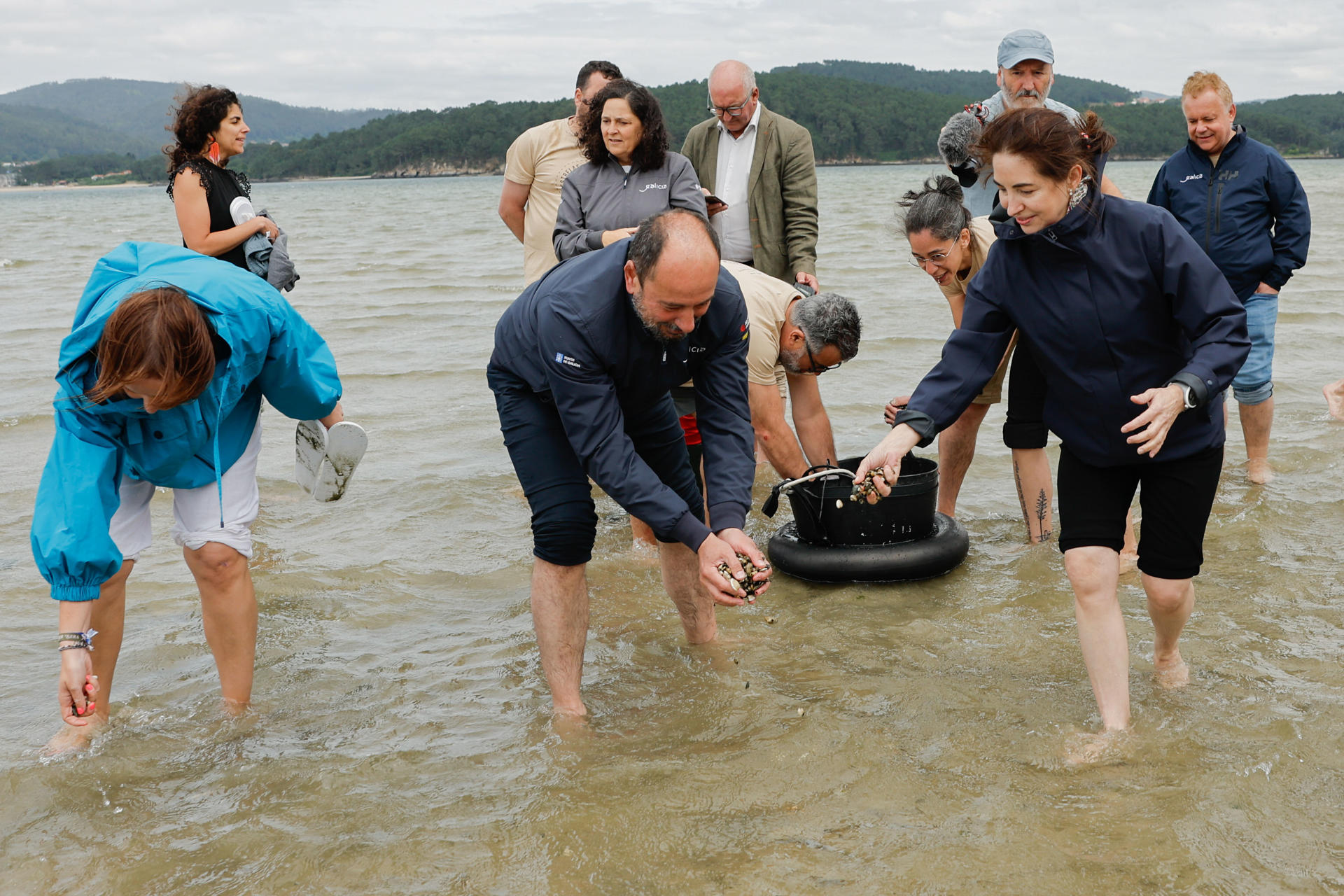 El director de Turismo de Galicia, Xosé Merelles, y la cheff, Elena Arzak (d), acompañados por mas de treinta cocineros que atesoran 70 estrellas Michelín, participan en la cría de semillas de marisco en la Praia do Testal, en la Ría de Muros y Noia, en el marco del evento solidario Estrellas Solidarias no Camiño, este lunes en Noia (A Coruña). EFE/ Lavandeira Jr