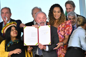 El presidente de Brasil, Luiz Inácio Lula da Silva (c), al sostener este martes, 3 de junio, una ley firmada por él que reserva un 30 % de los cargos públicos a personas negras, mestizas e indígenas, en el Palacio de Planalto, en Brasilia (Brasil). EFE/Andre Borges