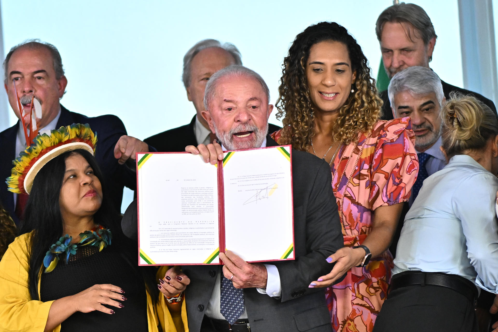 El presidente de Brasil, Luiz Inácio Lula da Silva (c), al sostener este martes, 3 de junio, una ley firmada por él que reserva un 30 % de los cargos públicos a personas negras, mestizas e indígenas, en el Palacio de Planalto, en Brasilia (Brasil). EFE/Andre Borges