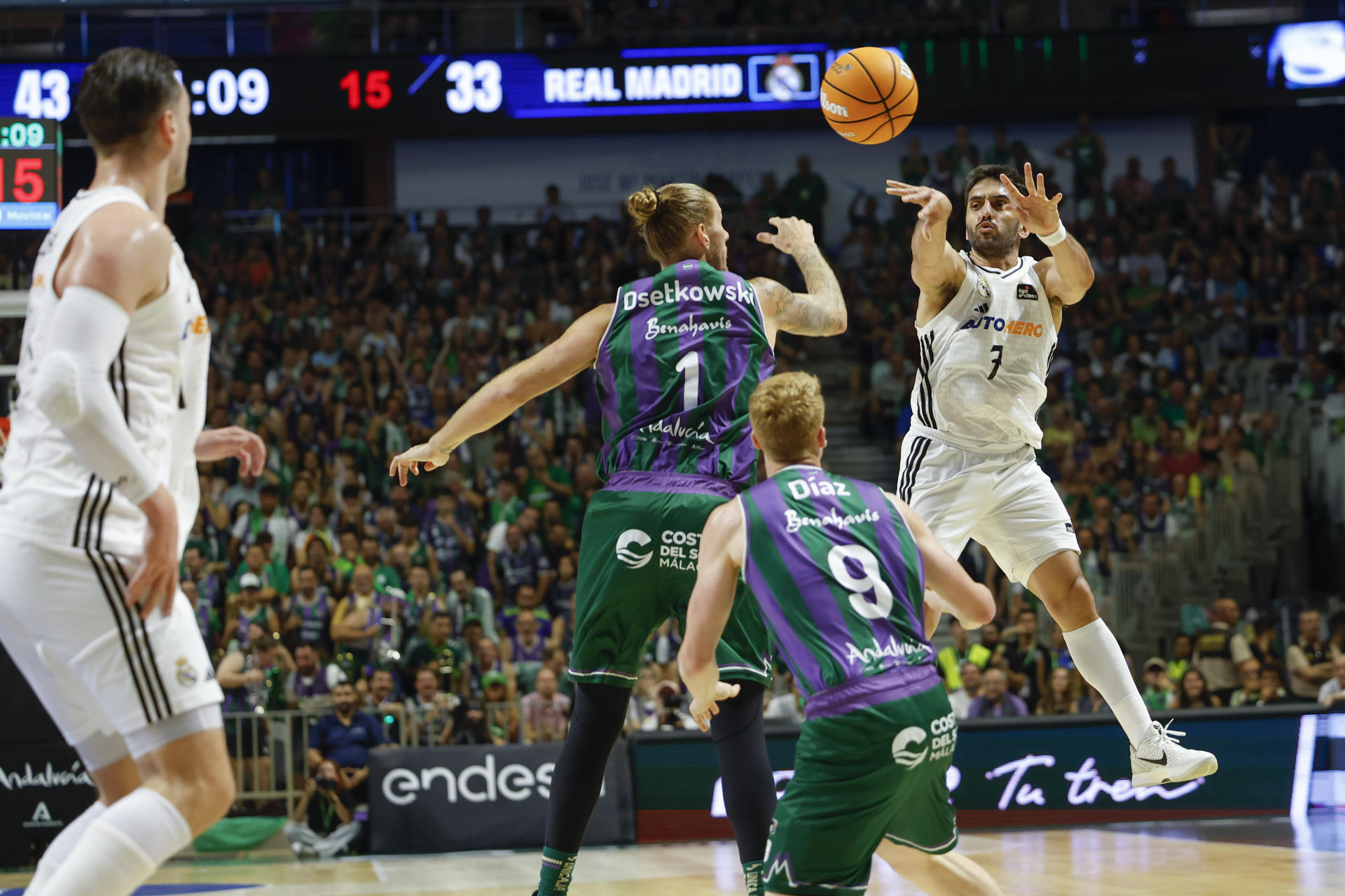 El base argentino del Real Madrid Facundo Campazzo (d) efectúa un pase ante el ala pívot estadounidense de pasaporte alemán de Unicaja, Dylan Osetkowski (2i) durante el cuarto partido de semifinales de la Liga Endesa de baloncesto que Unicaja y Real Madrid disputaron en el pabellón José María Martín Carpena, en Málaga. EFE/Jorge Zapata