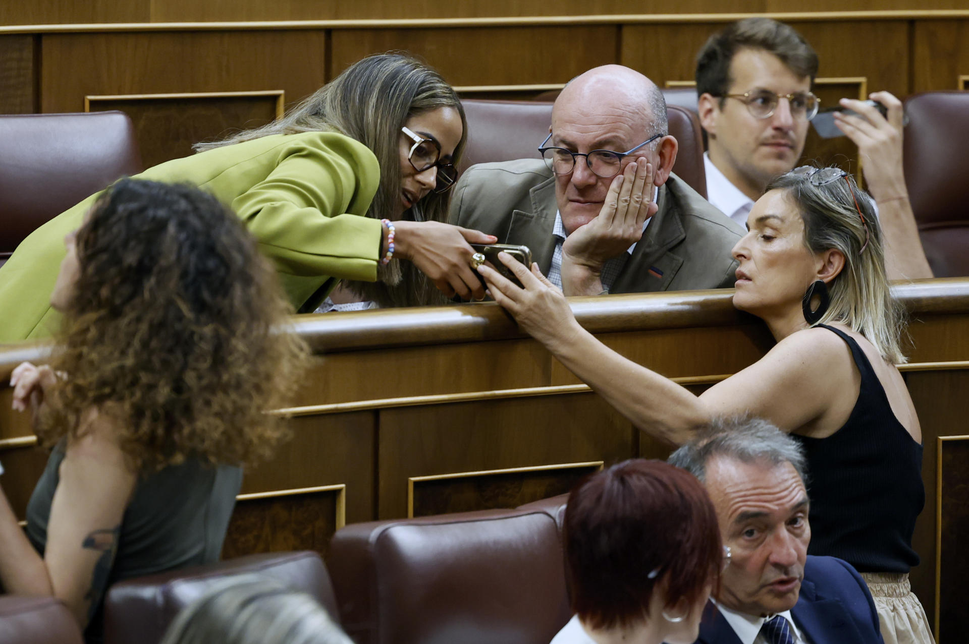 La diputada de Sumar Tesh Sidi muestra un móvil al diputado del PNV Mikel Legarda durante el pleno que este jueves se celebra en el Congreso. EFE/ Mariscal