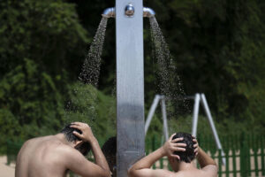 Dos personas se duchan en la playa de los Peligros este miércoles en Santander. EFE/Pedro Puente Hoyos
