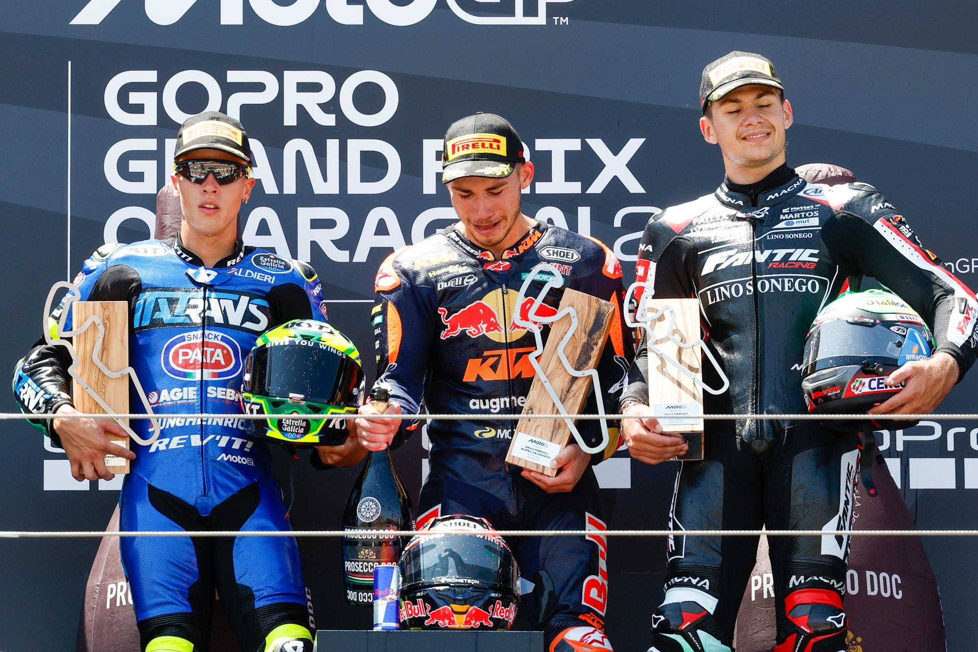 El ganador, el piloto turco Denis Öncü (d), del equipo Red Bull KTM Ajo, el segundo clasificado, el brasileño Diogo Moreira (i), de Italtrans Racing Team, y el tercer clasificado, el piloto belga Barry Baltus, del equipo Fantic Racing LINO SONEGO, en el podio de la carrera de Moto2 del Gran Premio de Aragón de MotoGP en el circuito Motorland de Alcañiz. EFE/Javier Cebollada