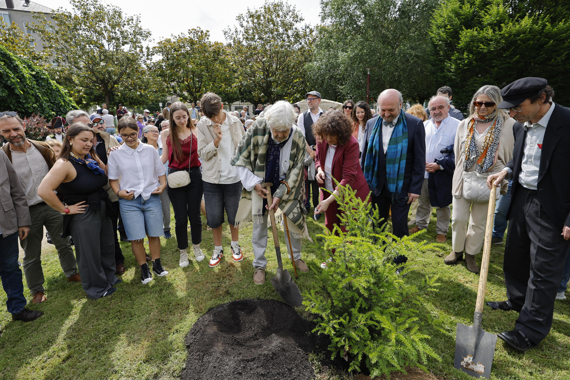 El histórico líder nacionalista Xosé Manuel Beiras (c), junto a la alcaldesa de Santiago, Goretti San Martín, y acompañado por su familia y amigos, planta un árbol dentro de los actos de homenaje que ha recibido Berias de la Asociación de Escritoras e Escritores en Lingua Galega (AELG) este sábado, en Santiago de Compostela. EFE/ Lavandeira jr