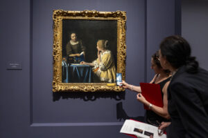 Personas observan el cuadro "La amante y la criada" durante la muestra "Cartas de amor de Vermeer, este miércoles en el museo Frick Collection en New York (EE.UU.). EFE/Ángel Colmenares