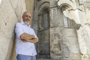 El doctor en Historia del Arte José Luis García Lloret posa ante la parte románica del ábside de la Seo del Salvador de Zaragoza, donde ha explicado a EFE en una entrevista los motivos que le han llevado a escribir una obra monumental que ahonda en tres maestros escultores del románico silense que dejaron huella de su arte en los territorios de Castilla, Navarra y Aragón. EFE/Javier Cebollada