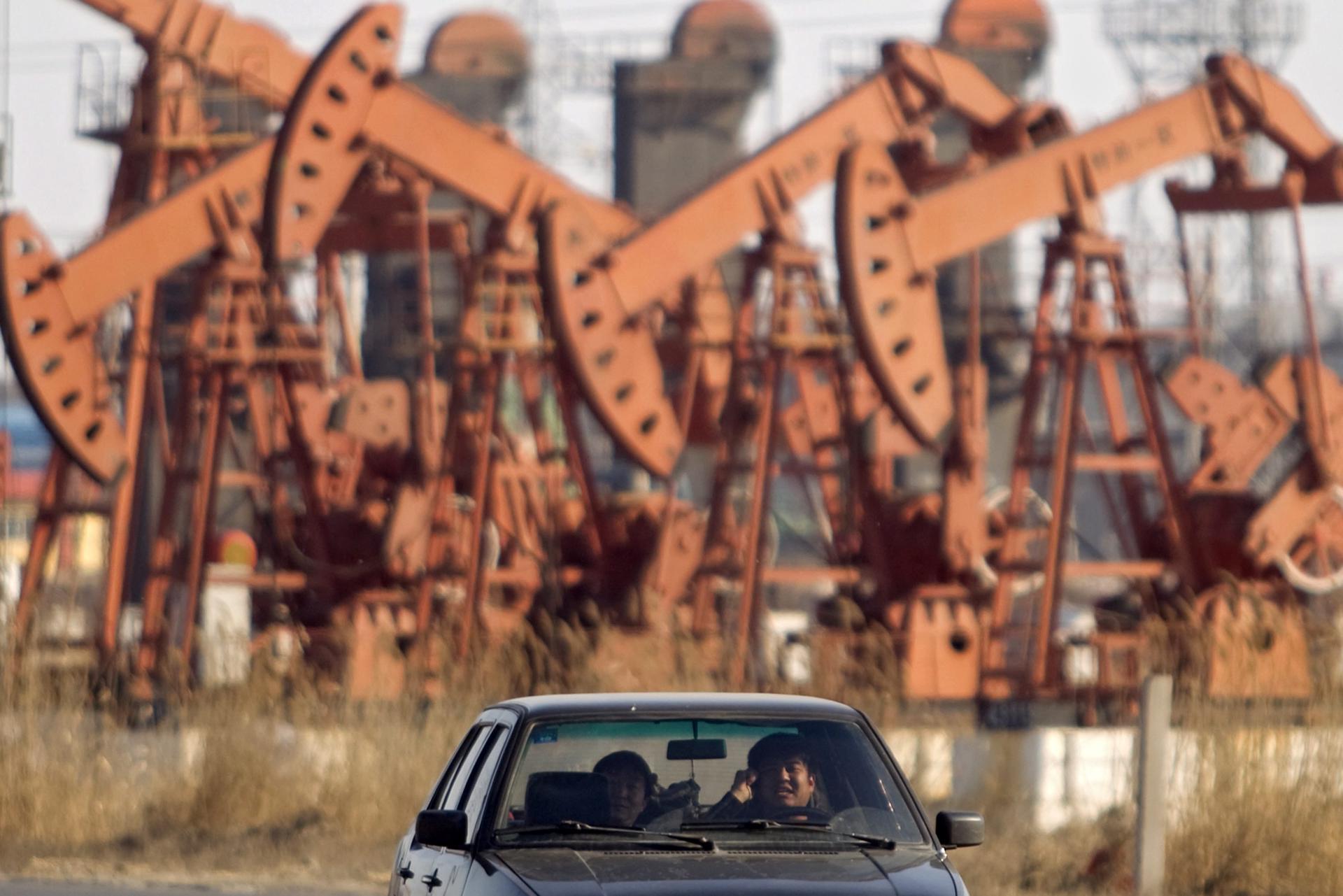 Fotografía de archivo que muestra un automóvil que circula junto a una plataforma petrolífera en el noreste de China. EFE/Sherwin