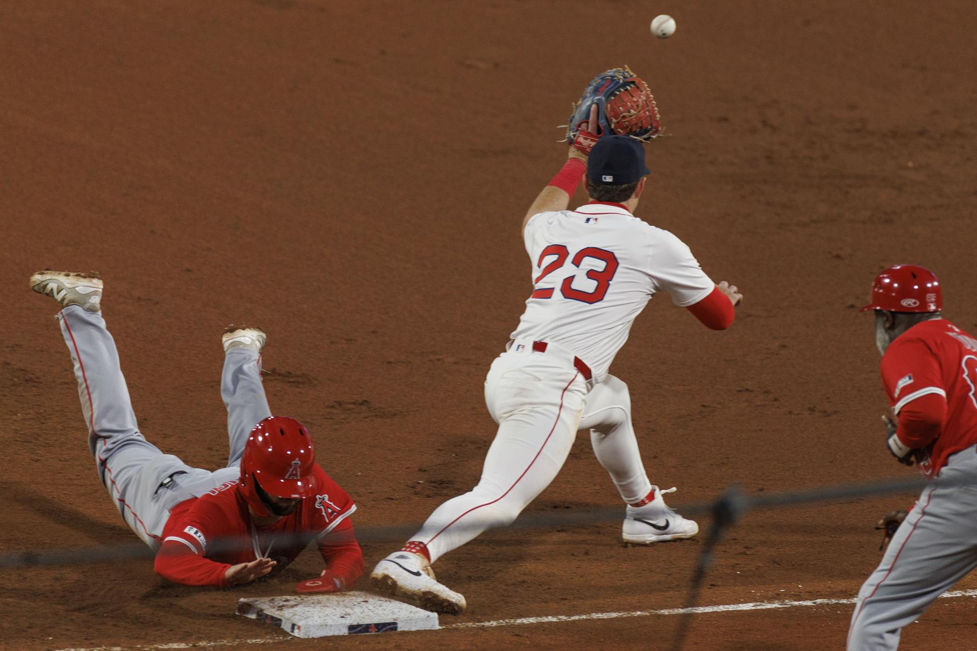 Nolan Schanuel (i) de los Angelinos de Los Ángeles, se sumerge en la primera base antes que la bola llegue al guante de Romy González, el guardián de esa almohadilla por los Angelinos de Los Angeles durante el partido jugado este lunes en Boston (Massachusetts). EFE/EPA/CJ GUNTHER
