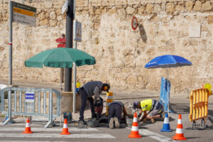Empleados trabajan en el suministro de agua bajo una sombrilla este miércoles en el puerto de Mahón, Menorca, en una jornada marcada por las altas temperaturas en la isla. EFE/ David Arquimbau Sintes