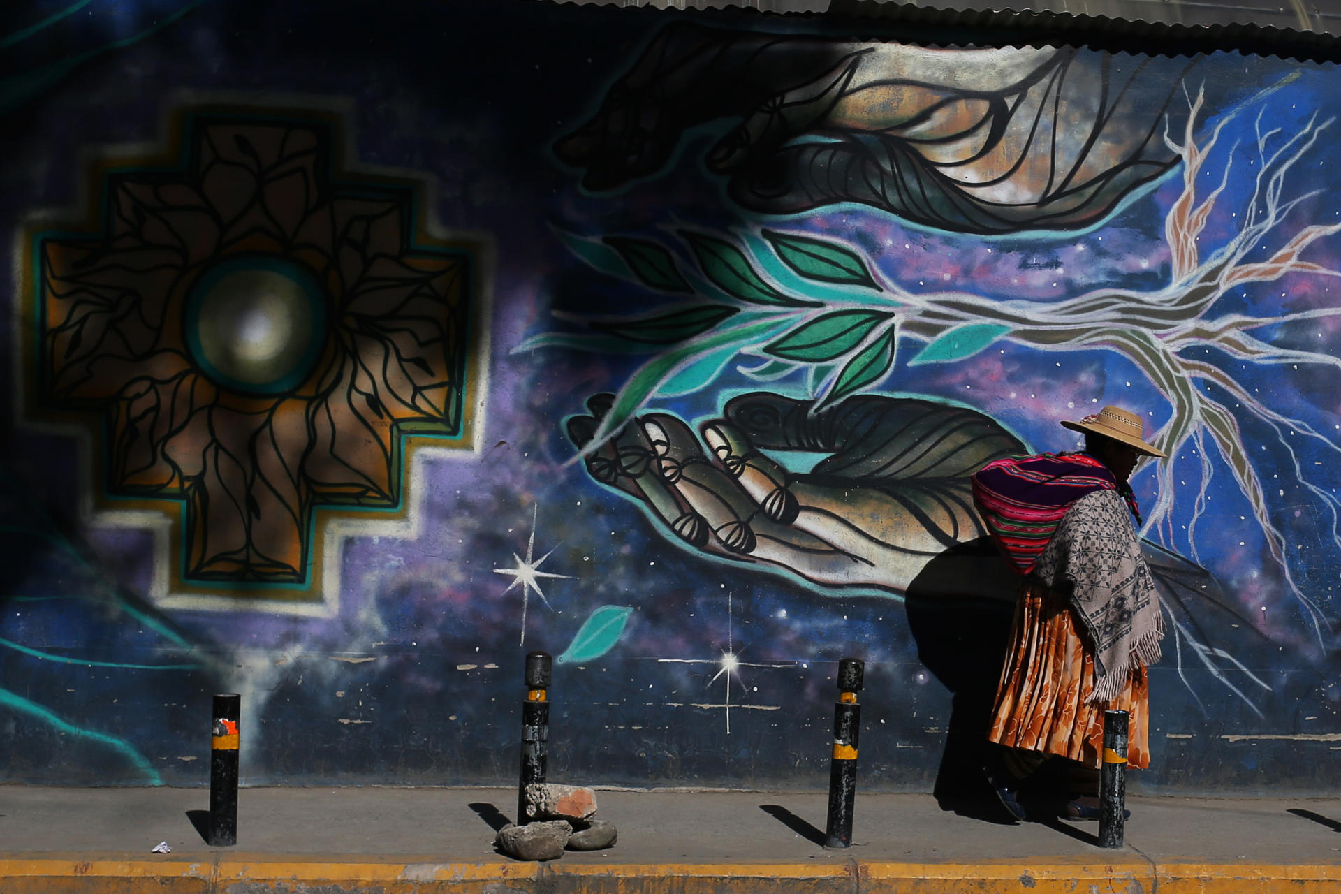 Una mujer aimara camina frente a un mural este martes, en El Alto (Bolivia). EFE/ Luis Gandarillas