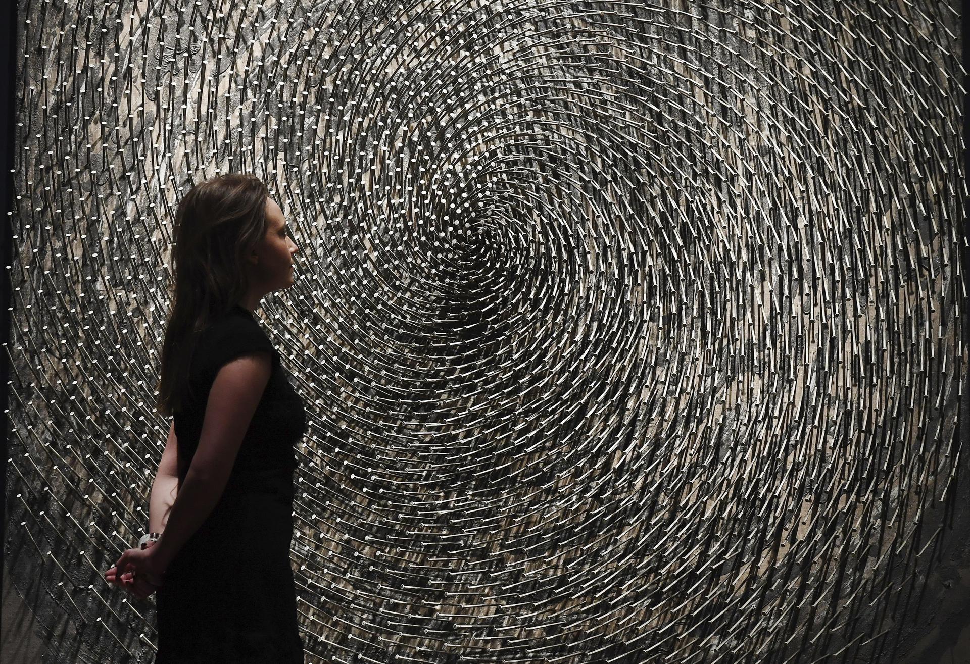 Imagen de archivo en la que una empleada de la casa Christie's contempla en Londres la obra "Spirale" del artista alemán Günther Uecker, fallecido este martes. EFE/Andy Rain
