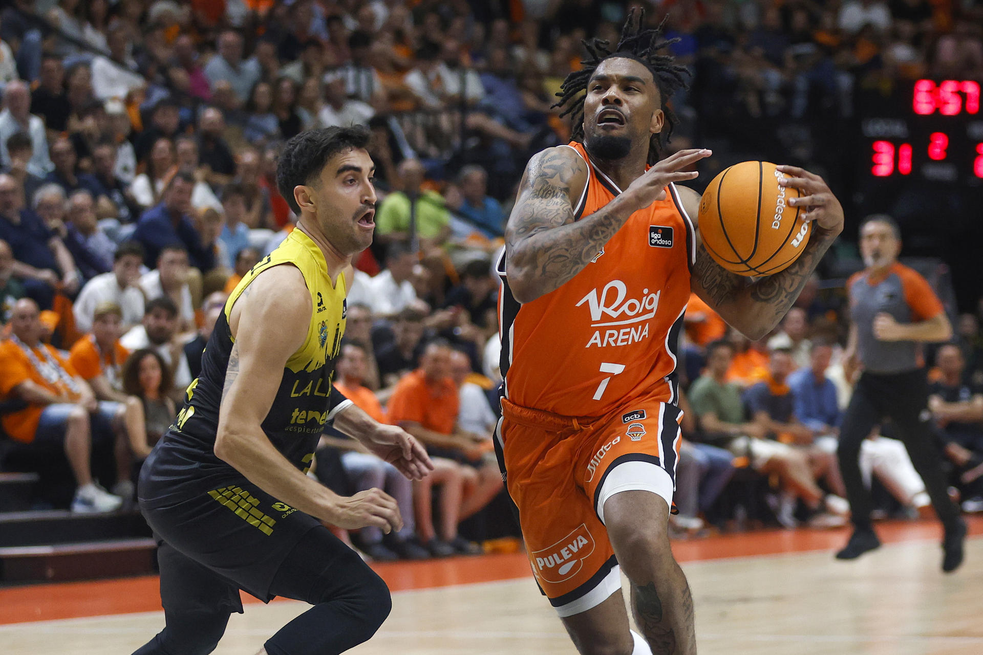 El base estadounidense de Valencia Basket, Chris Jones (d), con el balón ante el jugador de La Laguna Tenerife, Jaime Fernández, durante el primer encuentro de las semifinales de la Liga Endesa que disputaron en el pabellón de la Fuente San Luis de Valencia. EFE/Miguel Ángel Polo.