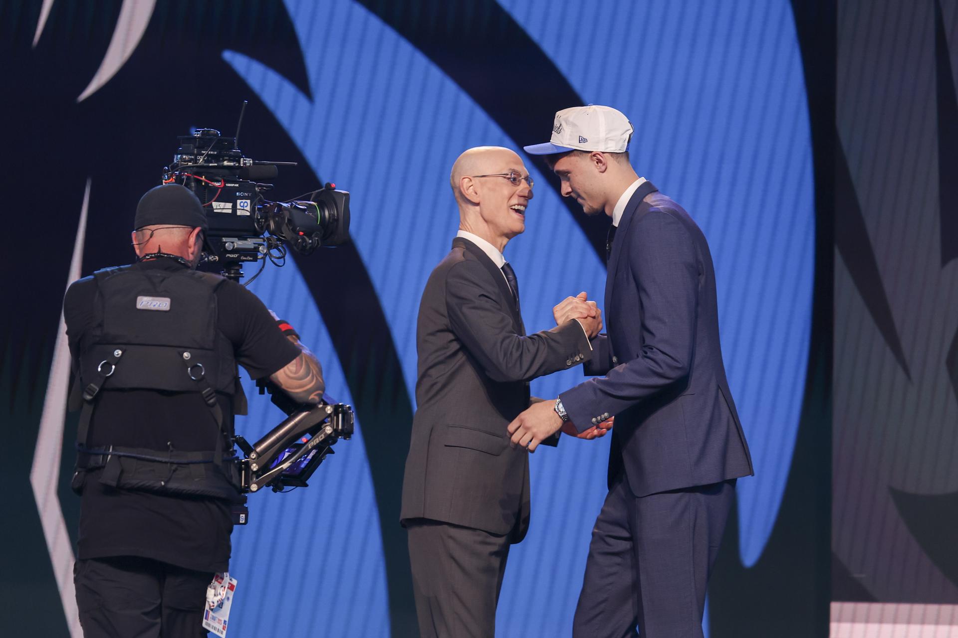 El jugador de baloncesto estadounidense Cooper Flagg (d) choca su mano con el comisionado de la NBA, Adam Silver, tras ser elegido número uno en el draft de la NBA por los Dallas Mavericks. EFE/SARAH YENESEL
