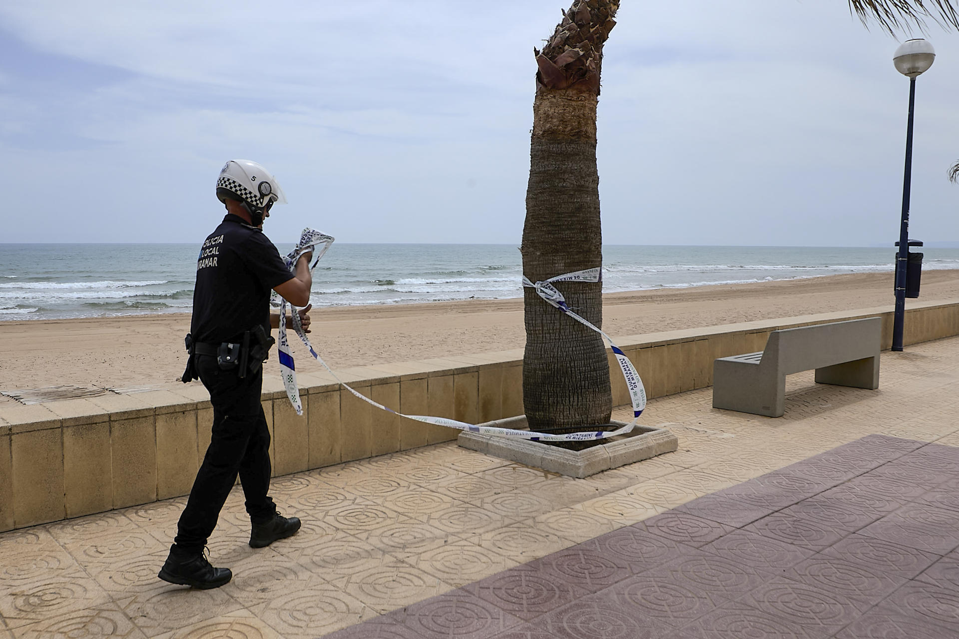 Un agente de la Policía Local abre el acceso a la arena en la playa de Miramar, pero se mantiene la prohibición de baño en las payas de Piles, Miramar y Daimús, y la prohibición de acceso en la de Bellreguard por el posible vertido marino, que está siendo analizado. EFE/Natxo Francés
