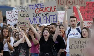 Decenas de activistas con pancartas, incluida una (c) que dice '¡todas las chicas contra la violencia!', fueron captados este jueves, 18 de junio, durante una protesta por el asesinato de una joven embarazada, frente a la sede del gobierno, en Bucarest (Rumanía). EFE/Robert Ghement
