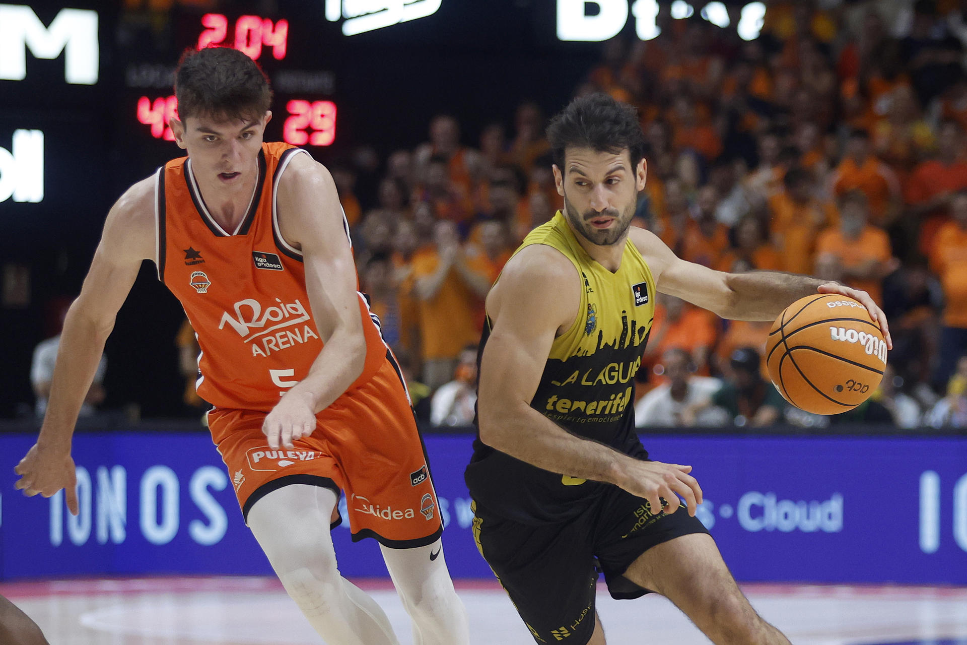 El escolta de La Laguna Tenerife Bruno Fitipaldo (d) avanza con el balón perseguido por Sergio de Larrea, del Valencia Basket, durante el primer encuentro de las semifinales de la Liga Endesa que Valencia Basket y La Laguna Tenerife disputaron en el pabellón de la Fuente San Luis, en Valencia. EFE/Miguel Ángel Polo.