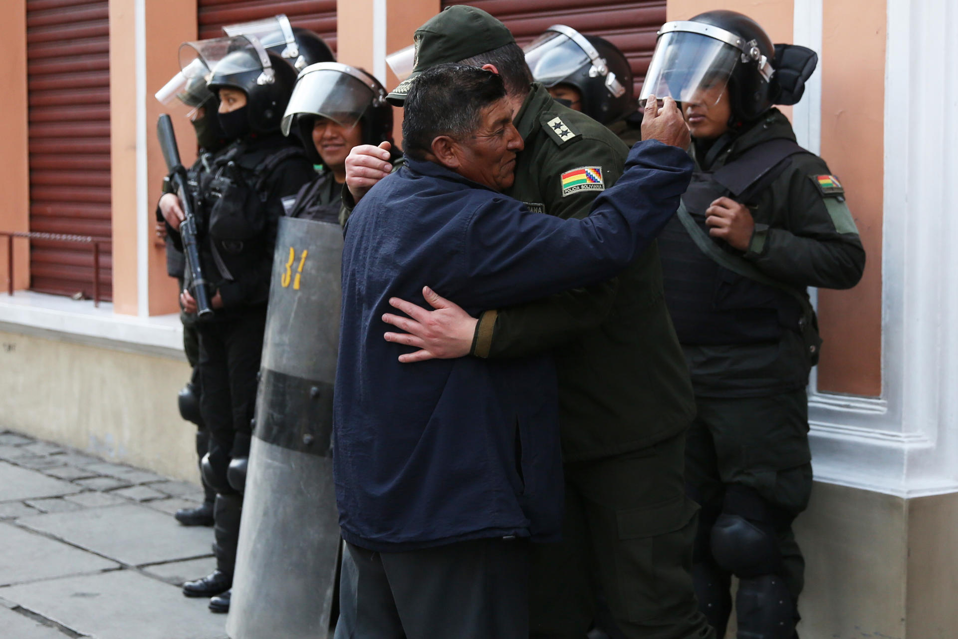 Un oficial jubilado abraza a un integrante de la Policía boliviana, durante una marcha pidiendo justicia por la muerte de sus compañeros durante enfrentamientos con seguidores del expresidente Evo Morales, este martes en La Paz (Bolivia). EFE/Luis Gandarillas